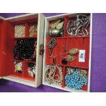 A jewellery box containing a selection of costume jewellery including strings of beads, hat pins,