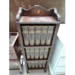 A small dark oak bookshelf with Charles Dickens volumes included