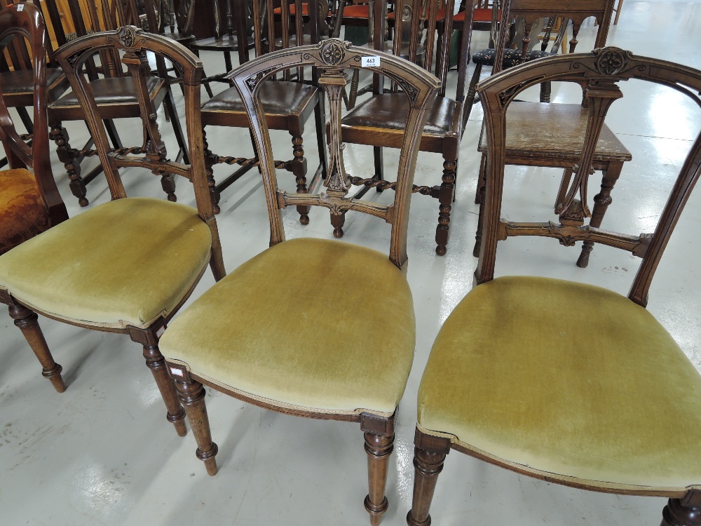 A set of three salon chairs with carved backs