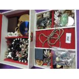 A jewellery box containing a selection of costume jewellery including brooches, beads, earrings,