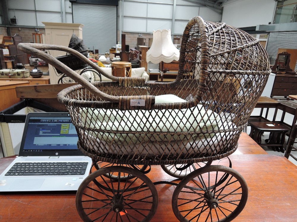 A vintage wicker style childs or dolls pram