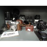 A selection of vintage photography equipment lens and cameras including Minolta 70 - 210 and 7000