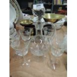 A clear glass decanter and goblet set with etched design