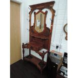 A late Victorian mahogany hall stand having mirror shield and carved panel decoration over glove box