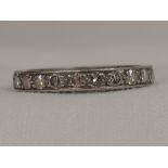A diamond full eternity ring having worn decoration to sides, no marks possibly platinum, size M