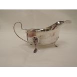 A silver sauce boat of plain form having shaped rim, trefoil paw feet and loop handle, Sheffield