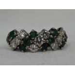 A lady's dress ring having a triple row of diamonds, total approx 0.5ct interspersed by emeralds,