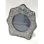 A silver photograph frame of shaped arched form having moulded cherubic decoration with navy