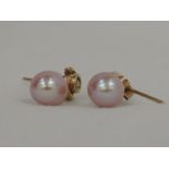 A pair of 9ct gold diamond stud earrings with pink baroque pearl drops