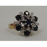 A lady's dress ring having a large sapphire starburst cluster with diamond chips in a raised