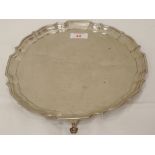 A silver salver having raised pie crust border, trefoil hoof feet and inscription to centre,