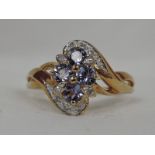 A lady's dress ring having a tanzanite and diamond cluster within diamond set crossover shoulders on