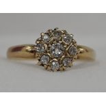 A lady's dress ring having a diamond daisy cluster on a cushion mount to moulded shoulders on an