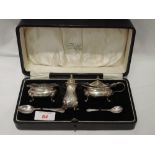 A cased three piece matched silver cruet set of oval form with paw feet, Birmingham mixed dates
