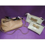 A tan leather and black patent shoulder bag and two ivory plastic toiletries bags with bow detail by
