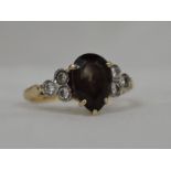 A lady's dress ring having a teardrop shaped smoky quartz flanked by a trio of diamonds to each side