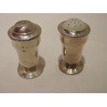 A pair of HM silver pepperettes of pedestal urn form having bakelite liners and screw lids,