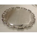 A silver salver of plain form having raised indented pie crust rim and trefoil shell and acanthus
