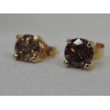 A pair of champagne diamond stud earrings, total approx 1ct weight in 18ct gold basket mounts