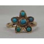 A lady's dress ring having a turquoise set flower head cluster on a yellow metal loop stamped
