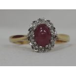 A lady's dress ring having a ruby cabouchon and diamond cluster in an illusionary setting on an 18ct