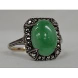 A lady's dress ring having an oval jade style cabouchon in a marciste set mount on a yellow metal