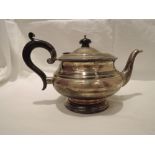 A silver teapot of plain circular form having hard wood handle on pedestal foot, Birmingham 1932,