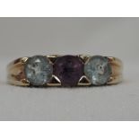 A lady's dress ring having a central amethyst flanked by two clear paste stones in a band setting on