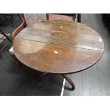 An early 19th century oak pedestal table having circular plank top on turned column and triple splay