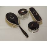 Four HM silver and tortoise shell dressing table items including two brushes, a glass pot with