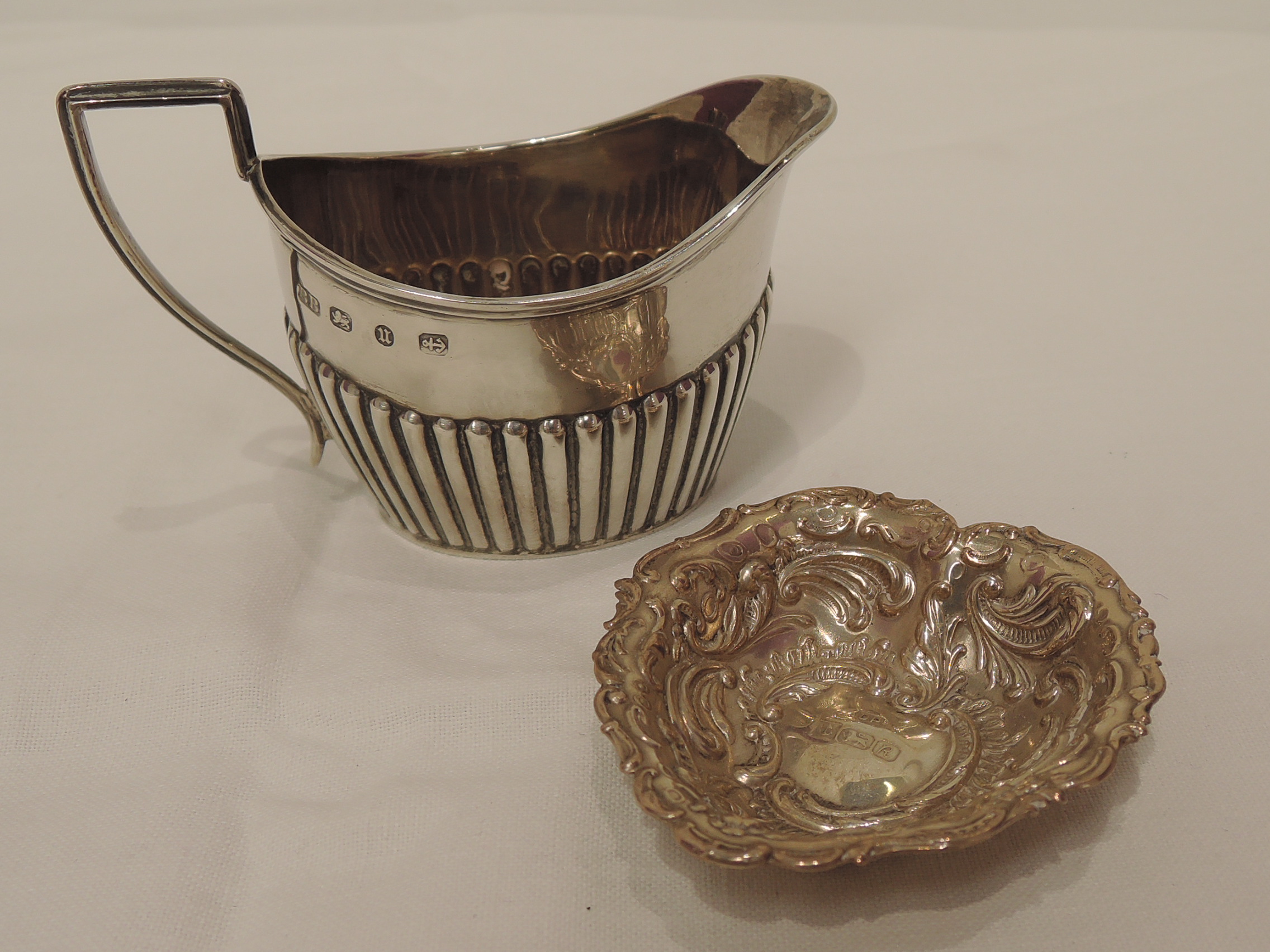 A Victorian silver cream jug having gadrooned decoration, reeded rim and architectural handle,