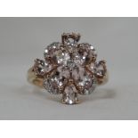 A lady's dress ring having a a pink gem stone floral cluster with diamond chip border on a 9ct