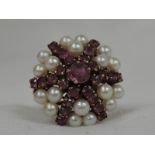 A lady's dress ring of over sized form having cultured pearl and ruby star burst cluster in a basket