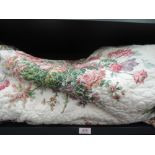 A quilted double bed cover having floral decoration on cream ground with tassel edge