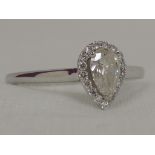 A lady's dress ring having a pear shaped diamond, approx .4ct surrounded by diamond chips in a