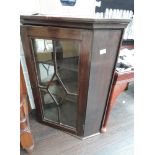 An early 20th century mahogany corner wall display cabinet having applique glass door