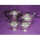 A four piece silver tea set of plain form having painted wooden handles and pedestal feet,