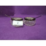 A pair of cut glass salts having HM silver collars and plated salt spoons with scallop bowls