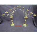 A pair of brass candelabrum of slant scroll and sconce design