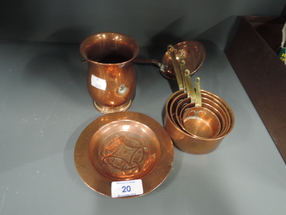 A selection of vintage copper wares including graduated measures and Celtic style dish