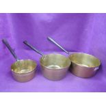 A set of three graduated brass and cast jam or sauce pans