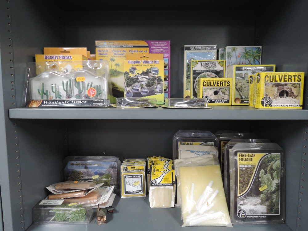 Two shelves of Woodland Scenics, Scenarama and similar HO scale trees and foliate kits, all boxed or