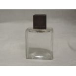 A glass perfume bottle of plain rectangular form having glass stopper and silver screw lid having