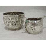 A Victorian silver sugar bowl and cream jug of circular form having Oriental repousse decoration and