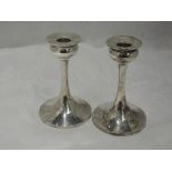 A pair of silver candlesticks having bulbous cups and tapered stems to weighted circular bases,