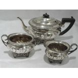 An Edwardian silver three piece tea set having gadrooned rim, repousse decoration, hard wood and