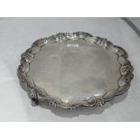 A silver salver of plain circular form having raised pie crust rim with scallop decoration and