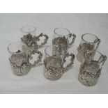 A set of six Edwardian tot glasses with silver holders having pierced and moulded decoration,