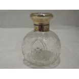 A glass perfume bottle of spherical form having cut floral decoration and silver pique work to