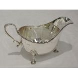 A silver sauce boat of plain form having gadrooned decoration to rim, moulded loop handle and